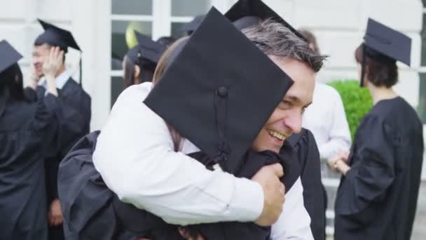 Los estudiantes en el día de la graduación son felicitados por los padres — Vídeo de stock