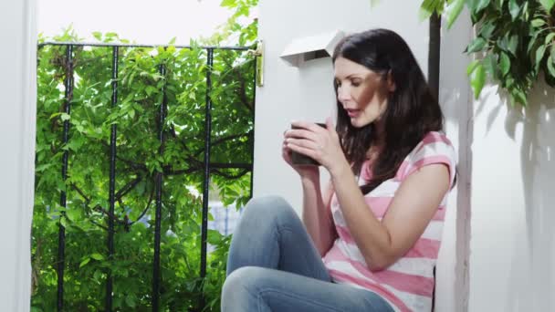 Woman sitting by window enjoying hot drink — Stock Video