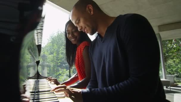Man en zijn liefde zitten piano spelen — Stockvideo