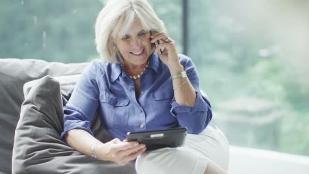 Mature woman making  phone call with tablet — Stock Video