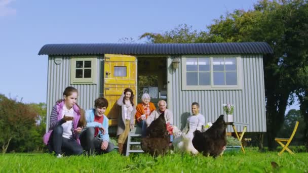Family group feeding chickens outside caravan — Stock Video