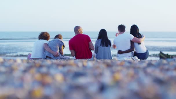 Friends sitting on beach and throwing stones — Stock Video