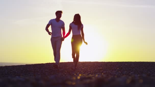 Pár drží za ruce a běží na pláži — Stock video