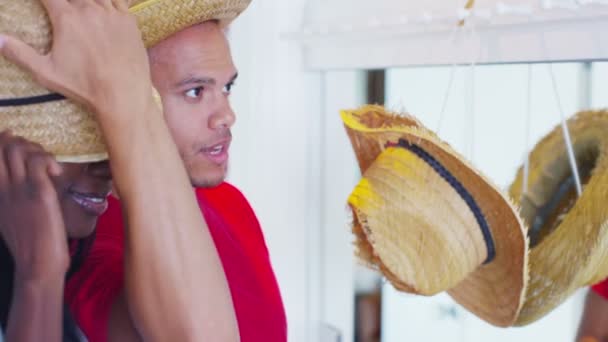 Couple trying on selection of straw hats. — Stock Video