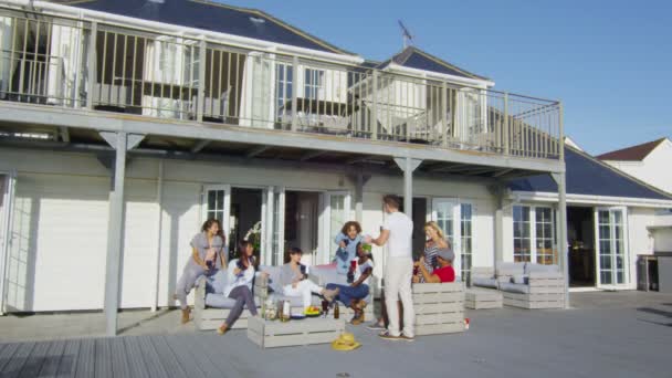 Freunde trinken vor dem Haus am Strand — Stockvideo