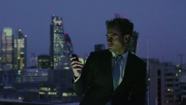 सफल व्यापारी रात में लंदन शहर स्काईलाइन के दृश्य को देखता है — स्टॉक वीडियो