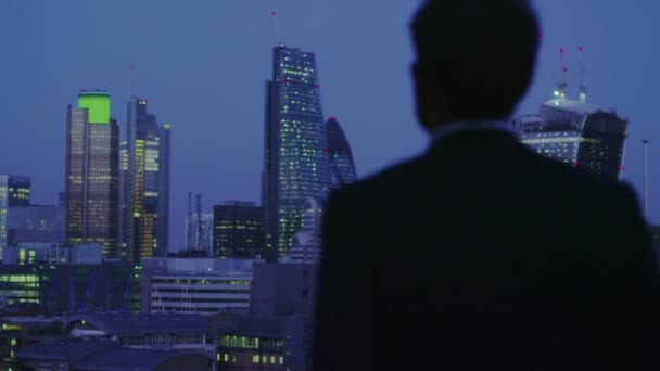 Un exitoso hombre de negocios contempla la vista del horizonte de la ciudad de Londres por la noche — Vídeo de stock