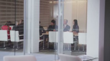 Büyük, modern bir ofis binasında yönetim kurulu toplantısında bir iş ekibi.
