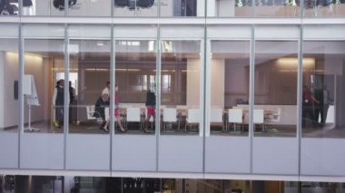 Büyük, modern bir ofis binasında yönetim kurulu toplantısında bir iş ekibi.