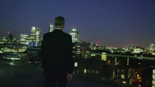 Un exitoso hombre de negocios contempla la vista del horizonte de la ciudad de Londres por la noche — Vídeo de stock