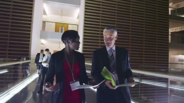 Pessoas de negócios em discussão enquanto caminham por um prédio de escritórios movimentado à noite — Vídeo de Stock