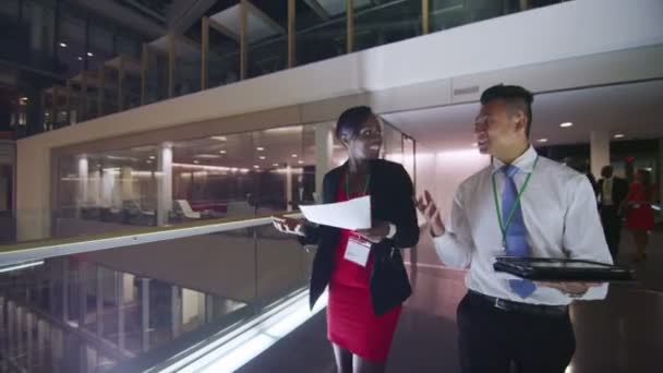 Business people in discussion as they walk through busy office building at night — Stock Video