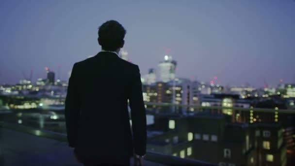 Homme d'affaires prospère regarde la vue sur les toits de la ville de Londres la nuit — Video