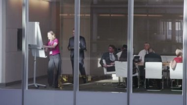 Büyük, modern bir ofis binasında yönetim kurulu toplantısında bir iş ekibi.