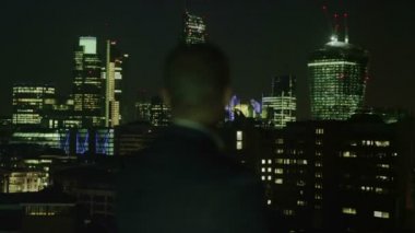 başarılı bir iş adamı Londra şehir manzarası görünümü geceleri dışarı bakar