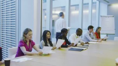 Büyük, modern bir ofis binasında yönetim kurulu toplantısında bir iş ekibi.