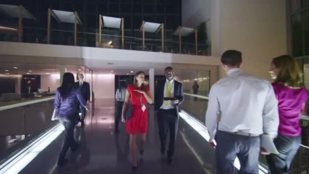 Business people in discussion as they walk through busy office building at night — Stock Video