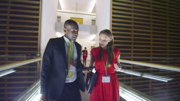 Business people in discussion as they walk through busy office building at night — Stock Video