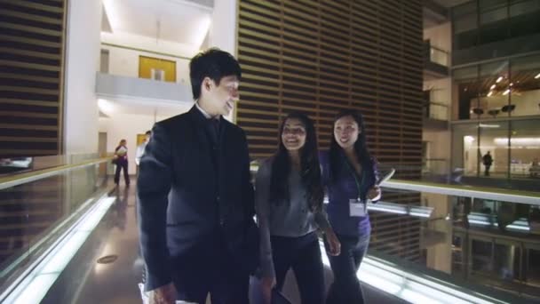 Gente de negocios en discusión mientras caminan por el concurrido edificio de oficinas por la noche — Vídeos de Stock