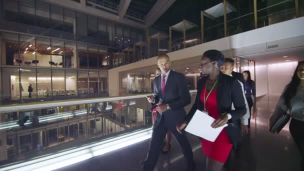 Gruppo di business diversificato attraente passeggiando per occupato edificio per uffici a notte — Stockvideo