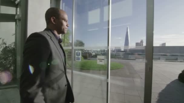 Бизнесмен выходит на открытую офисную террасу — стоковое видео