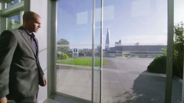 Бизнесмен выходит на открытую офисную террасу — стоковое видео