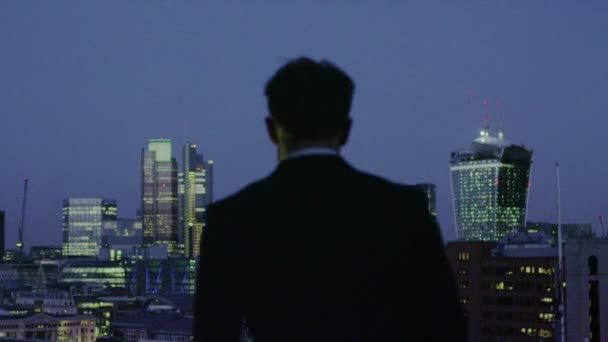 Un exitoso hombre de negocios contempla la vista del horizonte de la ciudad de Londres por la noche — Vídeo de stock