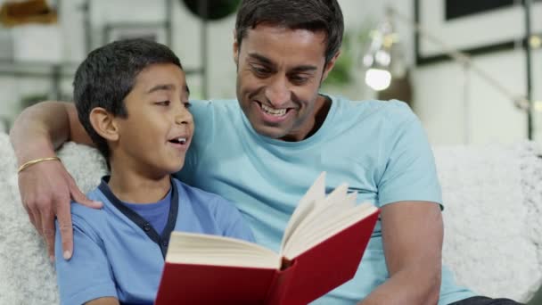Πατέρας και γιος να ξοδεψουν το χρόνο μαζί στο σπίτι, διαβάζοντας ένα βιβλίο — Αρχείο Βίντεο