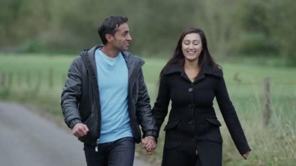 Muž a žena drží za ruce a užívat si procházku po polní cestě — Stock video