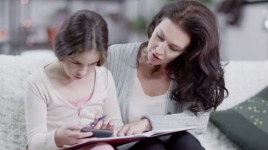 Anne kızı ödev yapmak için yardımcı olur.