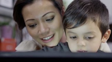 bir anne genç oğlu bir bilgisayar kullanmayı öğretir.