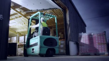 işçi forklifti bir ambarın dışında tersine çevirir.