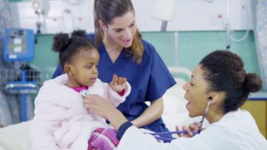kadın doktor stetoskop bir hastane, sevimli küçük kız incelemek için kullanır..