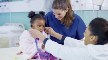 kadın doktor stetoskop bir hastane, sevimli küçük kız incelemek için kullanır..