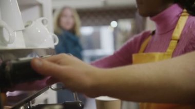 bir kahve makinesi ve müşterilerine hizmet kadın barista kapat