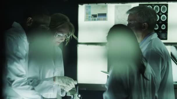 Ученые, работающие в темной лаборатории — стоковое видео