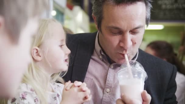 Schattige kleine jongen en meisje in een café genieten van hun milkshakes delen — Stockvideo