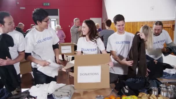 Благотворительные волонтеры сортируют пожертвованные товары — стоковое видео