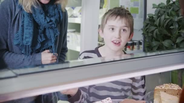 Lindo niño eligiendo una pastelería fresca en el mostrador de la panadería — Vídeos de Stock