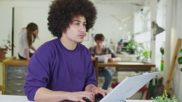 Joven estudiante masculino concentrándose mientras trabaja dentro de un espacio de estudio compartido — Vídeos de Stock