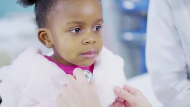 Female doctor uses a stethoscope to examine cute little girl in hospital. — Stock Video