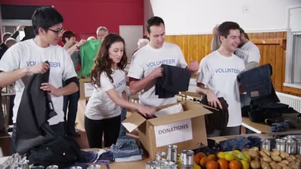 Благотворительные волонтеры сортируют пожертвованные товары — стоковое видео