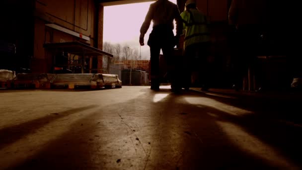 Trabalhadores que transportam mercadorias pela porta aberta de um armazém — Vídeo de Stock