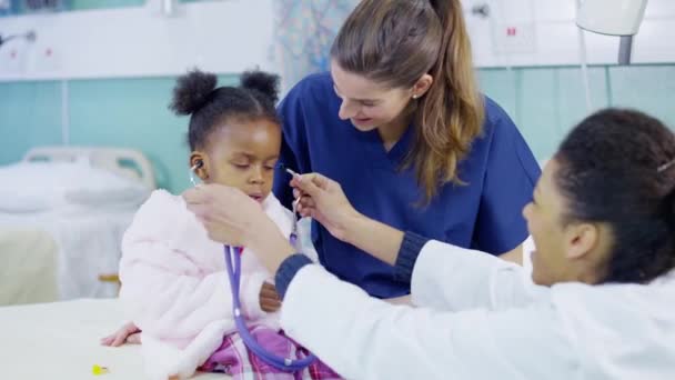 Ärztin benutzt Stethoskop, um süßes kleines Mädchen Herzschlag hören zu lassen