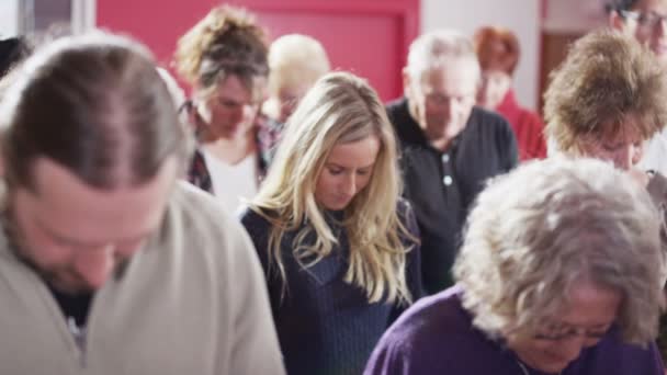 Iglesia grupo inclinar sus cabezas en oración — Vídeo de stock