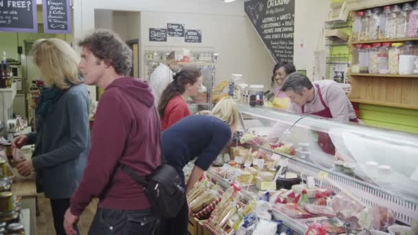Προσωπικό φιλικό delicatessen, που εξυπηρετούν τους πελάτες με ένα χαμόγελο στο μετρητή τυρί — Αρχείο Βίντεο