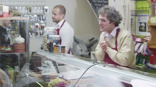 Equipe simpática que serve os clientes no balcão de queijos em um delicatessen — Vídeo de Stock