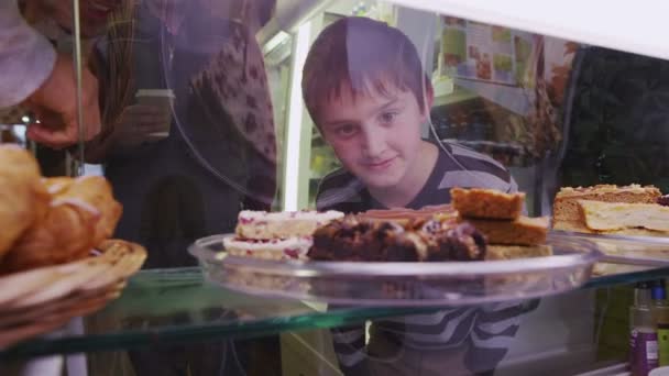 Lindo niño eligiendo entre una selección de pasteles frescos en un café o panadería — Vídeos de Stock