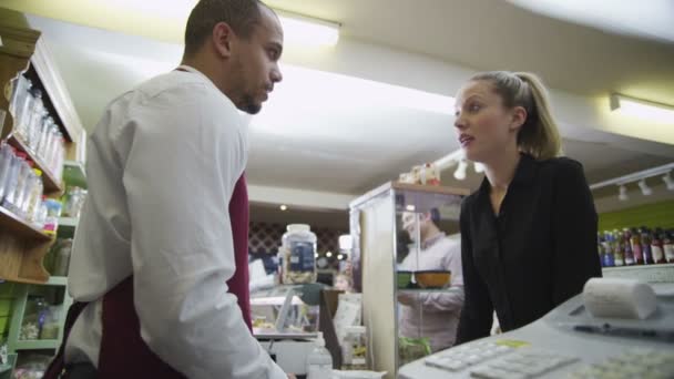 Jovem armazenista do sexo masculino servindo um cliente feminino atraente — Vídeo de Stock