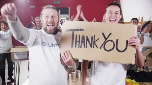 Two Charity workers hold up a Thank you sign as their fellow workers applaud — Stock Video